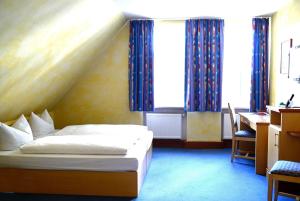 a bedroom with a bed and a desk and windows at Altstadthotel Haßfurt GbR in Haßfurt