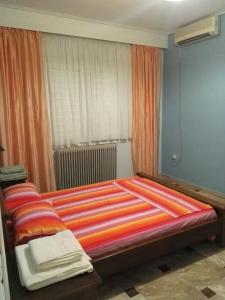 VromopoúsiにあるKaterina's houseのベッドルーム1室(大型ベッド1台、カラフルなストライプシーツ付)