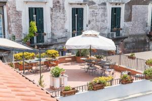 un patio con mesas, sillas y una sombrilla en B&B Nilo, en Nápoles