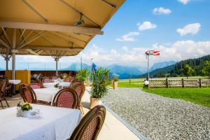 un restaurante con mesa, sillas y montañas en Hotel Marvia en Schwarzenberg im Bregenzerwald