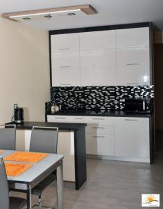 a kitchen with white cabinets and a table with chairs at Apartament Sun & Sand Polanki in Kołobrzeg