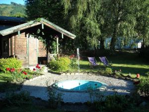 a small swimming pool in a yard with two purple chairs at Landhaus Griesser in Kaprun
