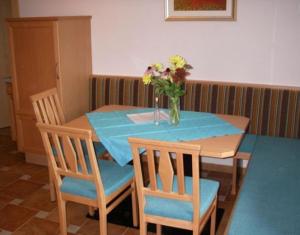 einen Tisch mit Stühlen und eine Vase mit Blumen darauf in der Unterkunft Apartment Schullehrer in Kauns