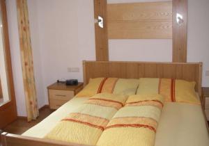 ein Schlafzimmer mit einem Bett mit einem Kopfteil aus Holz in der Unterkunft Apartment Schullehrer in Kauns