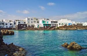 a group of houses on the shore of a body of water at Apartamento Tabayba Arena in Punta de Mujeres