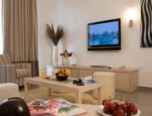 a living room with a television on a wall at Capital Coast Resort And Spa in Paphos