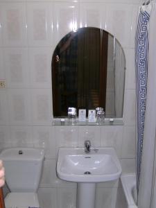 a white bathroom with a sink and a mirror at Hostal Alicante in Granada