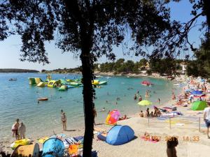 a beach with a bunch of people in the water at Mobile home - Kamp Olga in Banjole