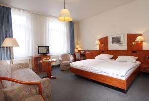 a bedroom with a bed and a couch and a chair at Hotel Stadt Hannover in Göttingen