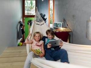 dwoje dzieci siedzących w hamaku z tabletem w obiekcie Ohboy Hotell w Malmö