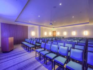 une salle de conférence avec des chaises bleues et un podium dans l'établissement The J House Greenwich Hotel, à Greenwich