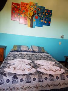 ein Bett in einem Schlafzimmer mit Gemälden an der Wand in der Unterkunft Hostel Iguazu Falls in Puerto Iguazú