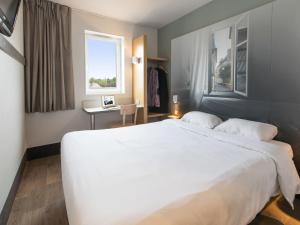 a large white bed in a room with a window at B&B HOTEL Angers 2 Université in Beaucouzé