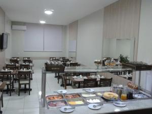 a restaurant with tables and chairs with food on display at Botucatu Hotel in Botucatu