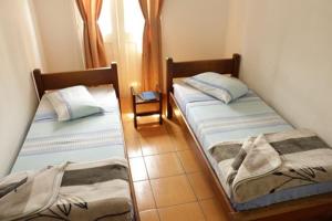 two twin beds in a room with a window at Hotel Carvalho in Bragança Paulista