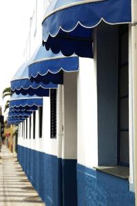 a blue and white building with blue awnings on it at Hotel Carvalho in Bragança Paulista