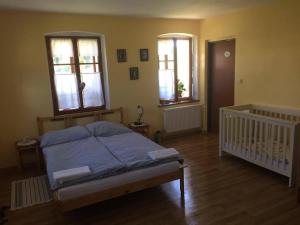 a bedroom with a bed and two windows and a crib at Rekreační dům u Marušky in Božanov