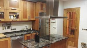 a kitchen with wooden cabinets and a granite counter top at Casa El balcón de Iria in Otero de Herreros