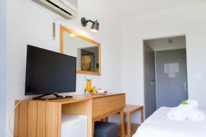 a bedroom with a television on a wooden desk at Hotel Hellas in Ancient Epidauros