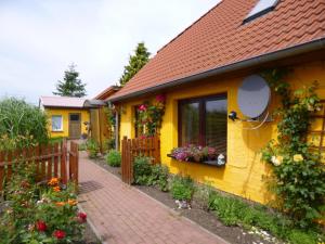 a yellow house with a fence and flowers at Ferienwohnungen Familie Jahn in Thesenvitz
