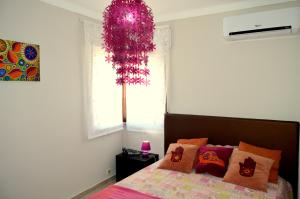 a bedroom with a bed and a pink chandelier at Apartamento Glamour in Manta Rota