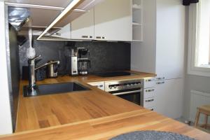 a kitchen with white cabinets and a wooden counter top at City Apartment Kauppakatu with Sauna in Iisalmi