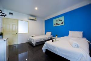 Cette chambre comprend 2 lits et un mur bleu. dans l'établissement Varinda Hostel, à Bangkok