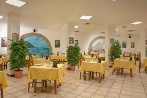 a restaurant with tables with yellow table cloths and plants at Hotel K2 in Numana