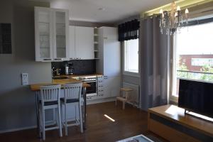 イーサルミにあるCity Apartment Kauppakatuの白いキャビネットとバースツール付きの島のあるキッチンが備わります。
