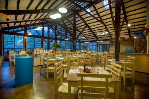 un restaurante con mesas y sillas de madera y ventanas en Tierra Viva Valle Sagrado Hotel, en Urubamba