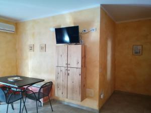 Habitación con mesa y TV en la pared. en Case Vacanza Villa Doria, en Valledoria