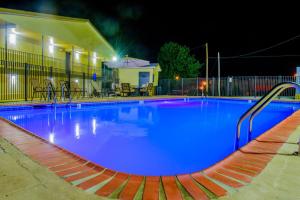 duży basen w nocy z niebieskim oświetleniem w obiekcie Days Inn & Suites by Wyndham Athens w mieście Athens