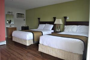 two beds in a hotel room with white sheets at Carrier Motor Lodge in Newington
