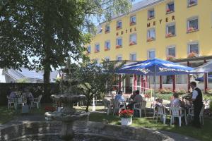 a group of people sitting at tables in front of a hotel at Hotel Meyer in Beaufort