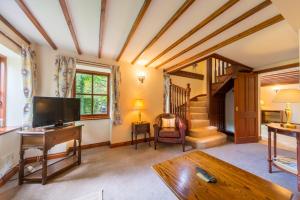 a living room with a television and a staircase at Glen-Yr-Afon House Hotel in Usk