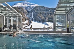 a woman in a swimming pool with a mountain in the background at Hotel Nassereinerhof in Sankt Anton am Arlberg
