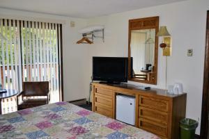 1 dormitorio con cama y vestidor con TV en Kancamagus Lodge en Lincoln
