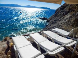 a group of chaise lounges on the rocks near the ocean at Rosys Little Village in Skala