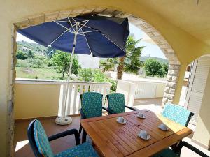 a wooden table and chairs with an umbrella on a porch at Apartments Barbara in Banj