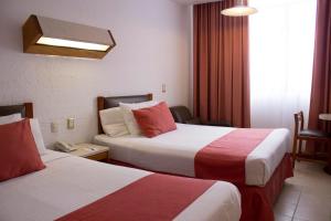 Habitación de hotel con 2 camas con sábanas rojas y blancas en Hotel Enriquez, en Coatzacoalcos