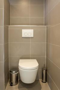 a bathroom with a toilet in a tiled wall at Slapen aan de Bosweg in Zoutelande