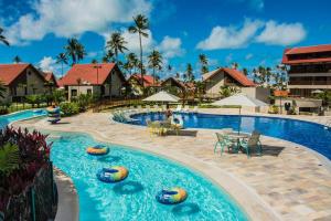 a pool at a resort with chairs and tables at Oka Resort in Porto De Galinhas