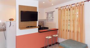 a living room with a flat screen tv and stools at Ancoradouro Flats in Abraão