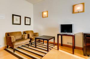 a living room with two chairs and a television at Hotel Alvorada in Estoril