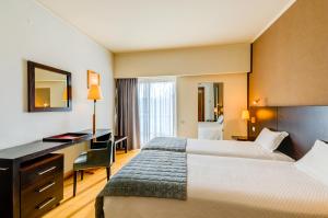 a hotel room with two beds and a desk at Hotel Alvorada in Estoril