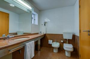 a bathroom with a sink and a toilet and a mirror at Hotel Alvorada in Estoril