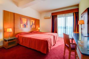 a hotel room with a red bed and a desk at Hotel Alvorada in Estoril