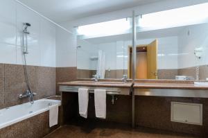a bathroom with a tub and a sink and a mirror at Hotel Alvorada in Estoril