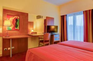 a hotel room with a bed and a desk with a computer at Hotel Alvorada in Estoril