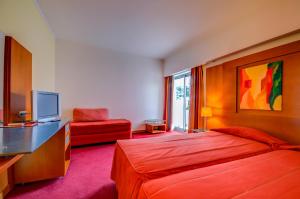 a hotel room with a bed and a television at Hotel Alvorada in Estoril
